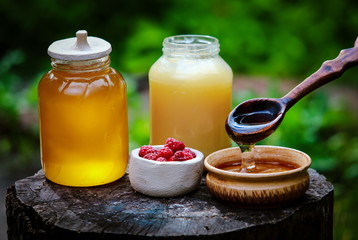 fresh sweet honey dripping in a wooden spoon in a ceramic bowl