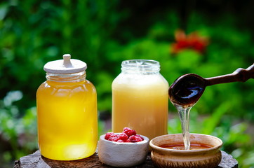 fresh sweet honey dripping in a wooden spoon in a ceramic bowl