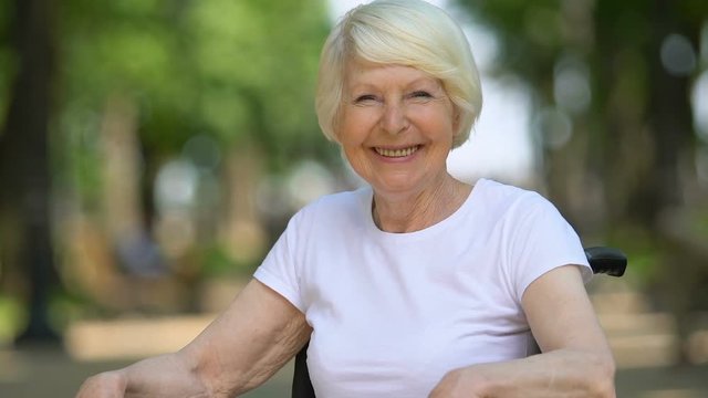 Smiling woman in wheelchair enjoying fresh air, comfortable equipment, close-up