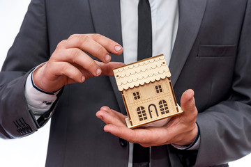 Male hands holding wooden house model close up