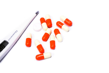 Capsule medicine of drug and electric medical thermometer on white background.