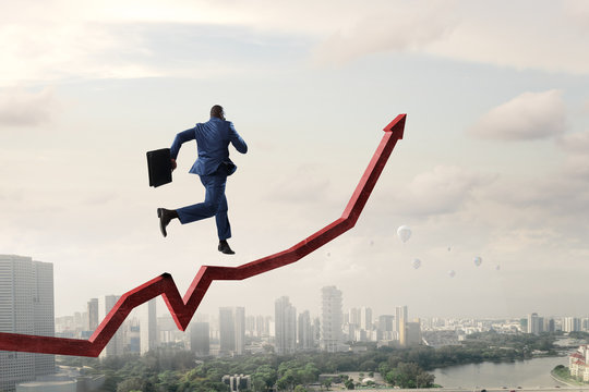 Black businessman running on red increasing arrow