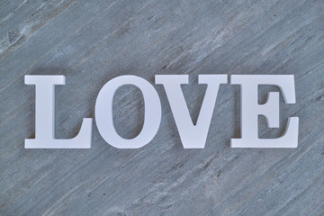 The inscription word love in white color on dark marble. White letters are on top of a marble slab.