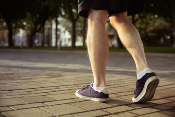 Senior man as runner at the city's street. Close up shot of legs in sneakers. Caucasian male model jogging and cardio training in summer's morning. Healthy lifestyle, sport, activity concept.
