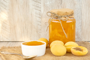 Home made organic apricot jam in glass jar and ripe apricots on wooden rustic table