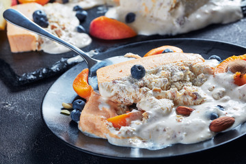 Italian summer dessert, a portion of melted Sicilian Almond apricot melon Semifreddo served on a black plate with fruits and berries, view from above, close-up