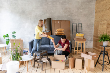 Happy smiling couple moving in a new house and unpacking cartons boxes, relocation and renovation concept