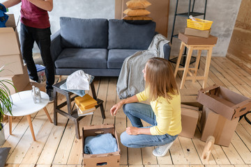 Happy people packing cardboard box, concept moving house. Young couple moving to a new apartment together. Relocation concept