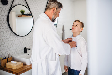 Mature father with small son getting dressed in the bathroom in the morning.