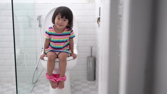 pooping in the toilet. cute asian kid push it hard while sitting on toilet