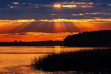 Romantyczny zachód słońca nad jeziorem z promieniami słońca w chmurach