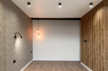 Modern new empty room with gray and wooden walls, lamps and hardwood floor, copy space. New apartment  in loft style