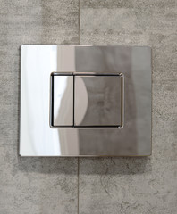 Economic toilet flush press with two separate buttons on grey wall in luxury hotel, copy space