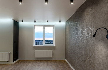 Large new living room in modern apartment with window, grey walls and led lamps on ceiling, copy space