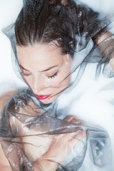 beautiful sensual woman creative portrait with black tulle in milk bath