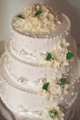 Obraz na płótnie Canvas three-tier wedding cake with cream roses and green foxes
