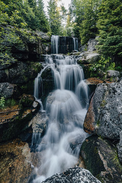 Waterfall photograph. Long exposure photo of a beautiful waterfall of Jedlova, Jizerske mountains, Czechia. Motion blurr water in a mountain creek in a deep forest. Alaska like stream with a rocks.