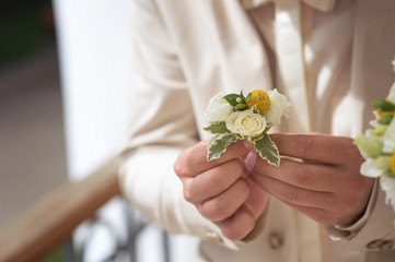 The groom holds a boutonniere, cream beautiful roses and a yellow accent