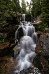 Waterfall photograph. Long exposure photo of a beautiful waterfall of Jedlova, Jizerske mountains, Czechia. Motion blurr water in a mountain creek in a deep forest. Alaska like stream with a rocks.