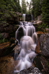 Waterfall photograph. Long exposure photo of a beautiful waterfall of Jedlova, Jizerske mountains, Czechia. Motion blurr water in a mountain creek in a deep forest. Alaska like stream with a rocks.