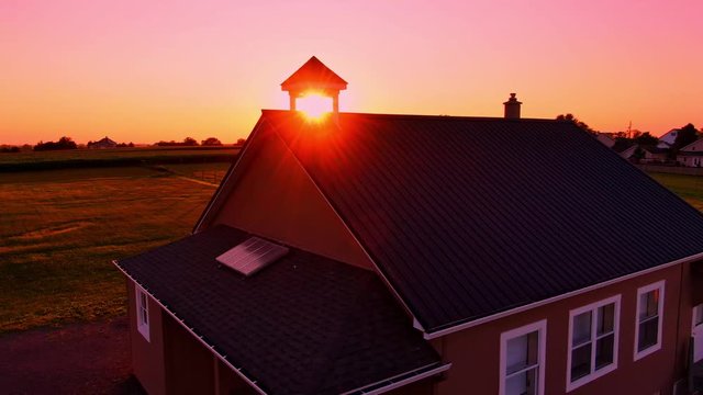 Late evening sunset behind the Schoolhouse in the Amish community Intercourse Pennsylvania USA. Slow right to left pan with drone