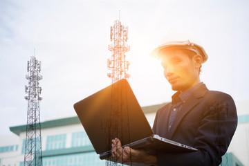 Double exposure Businessman holding computer notebook and Telephone and internet transmission towers
