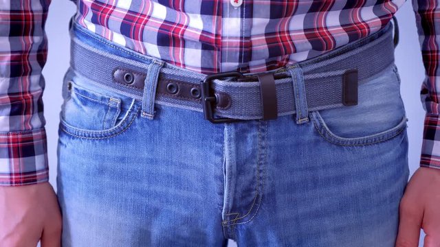 Man is touching his dick in jeans and slapping by hand. Playful mood, hand closeup. He is wearing jeans and plaid shirt, waist closeup.
