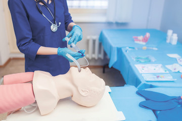 help emergency with complications in the respiratory tract.. introduction endotracheal tube (ETT) into trachea ensure airway patency. female medical student performs procedure exam. CMYK