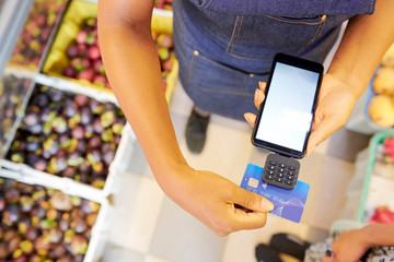 Close-up of saleswoman paying with special portable computer by credit card in the supermarket