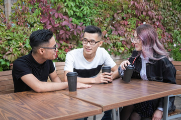 Three young hipsters sitting in a cafe and drink coffee.