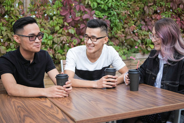 Three young hipsters sitting in a cafe and drink coffee.