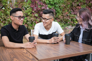 Three young hipsters sitting in a cafe and drink coffee.