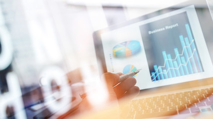 Businessman analyzing sales data and pointing at business graph chart growth and progress on laptop...