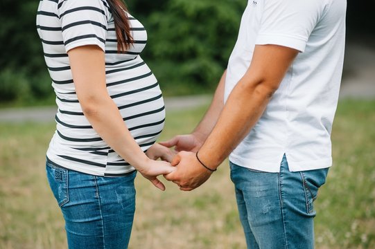 Image of pregnant couple. Husband touching his wife belly with hands. Pregnant woman outdoors