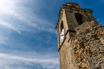 Fototapeta na wymiar Old bell tower with clock on blue sky with clouds. Church of St. Francis, Vernazza village. Cinque Terre, Liguria, La Spezia province, Italy, Europe. UNESCO world heritage site
