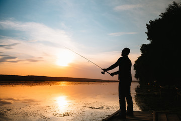 Fishing. spinning at sunset. Silhouette of a fisherman