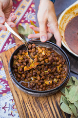 Black chickpeas. Kala chana masala with gravy. Woman hands holds, take spicy Indian traditional food.