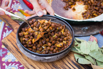 Black chickpeas. Kala chana masala with gravy. Woman hands holds, take spicy Indian traditional...