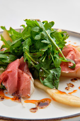 Salad with jamon, pear and arugula isolated on white