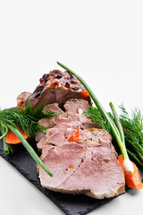 Big loaf of baked meat decorated with fresh vegetables isolated on white