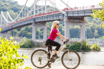 Young female traveler standing with bicycle on the street near the river in city. Traveling