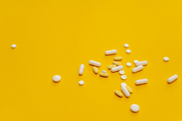 Tablets, pills and other medicine scattered on the orange background. Treatment of illness, malaise.  - obrazy, fototapety, plakaty