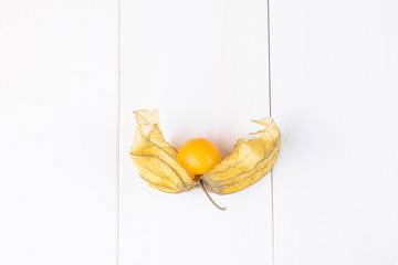 Physalis fruit (Physalis Peruviana) on a white wooden background close-up. Cape Gooseberry.  Minimalism, a place for text.