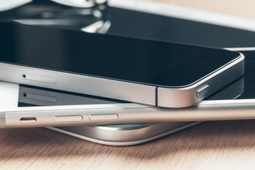 Digital tablet and mobile phone. Electronic devices on wooden table, close up.