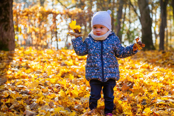 baby girl throwing the fallen leaves