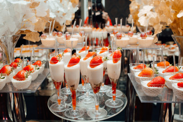 Table with sweets, buffet with cupcakes, candies. Sweets with strawberries. Delicious wedding reception candy bar dessert table. Candy bar. 