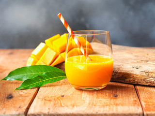 Mango smoothies glass with fresh mango fruit on wooden table for summer fruit drink concept.