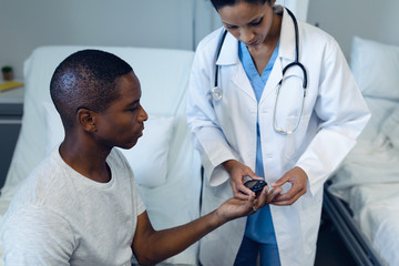 Female doctor taking patients blood sample with lancet pen in the ward