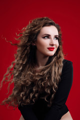 Portrait of a young beautiful brunette girl with long hair. Fashion studio portrait of beautiful smiling woman with Afro curls hairstyle. Fashion and beauty