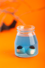 Halloween concept - two artificial eyes in a blue liquid on a orange background